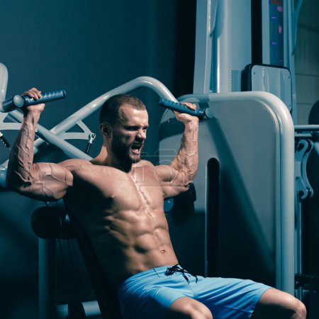 Foto de Retrato de un hombre musculoso fuerte haciendo ejercicio de tracción en el gimnasio moderno - Imagen libre de derechos