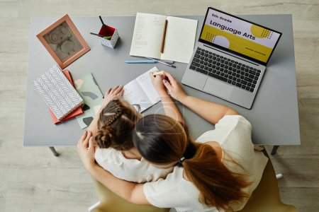 Photo for Top view at caring mother embracing daughter while studying together or doing homework, copy space - Royalty Free Image