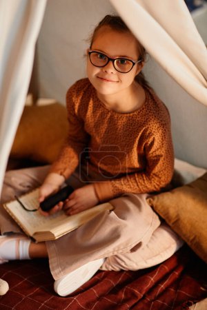 Photo for High angle portrait of young girl with down syndrome in cozy play tent smiling at camera - Royalty Free Image
