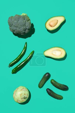 Foto de Vista superior mínima de la composición de verduras verdes sobre fondo azul brillante, alimentación saludable y concepto vegano, espacio de copia - Imagen libre de derechos
