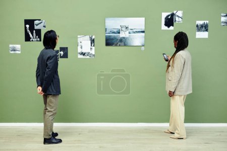 Téléchargez les photos : Horizontal plan large de jeune asiatique homme et femme noire passer du temps libre visiter moderne noir et blanc exposition de photographie dans la galerie d'art - en image libre de droit