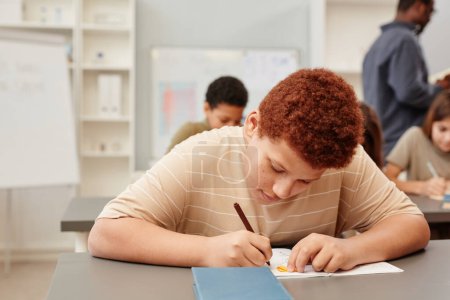 Foto de Retrato de adolescente pelirrojo trabajando duro mientras estudiaba en el aula de la escuela - Imagen libre de derechos
