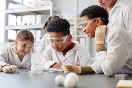 Photo for Portrait of African American boy enjoying enjoying science experiments in chemistry class and wearing protective gear - Royalty Free Image