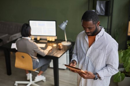Photo for Waist up portrait of black businessman using digital tablet while wearing casual clothes in modern office space - Royalty Free Image