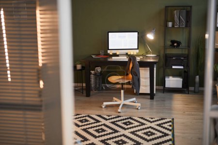 Foto de Imagen de fondo del acogedor espacio de oficina con lugar de trabajo iluminado por lámparas tarde en la noche, espacio de copia - Imagen libre de derechos