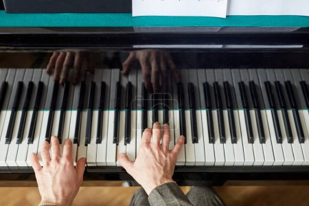 Téléchargez les photos : Gros plan des mains masculines poussant sur les touches noir et blanc et jouant de la musique sur piano à queue - en image libre de droit