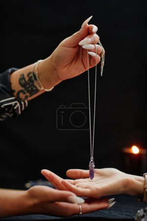 Photo for Side view close up of fortune teller holding magic crystal over hand of young woman and reading her destiny in spiritual seance - Royalty Free Image