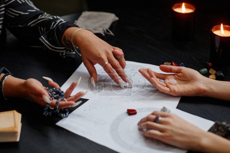Photo for Close up of fortune teller pointing at astrology chart during spiritual seance with young woman - Royalty Free Image