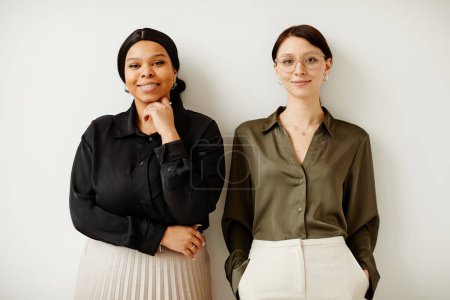 Photo for Minimal portrait of two young successful business women smiling with joy while standing against neutral background - Royalty Free Image