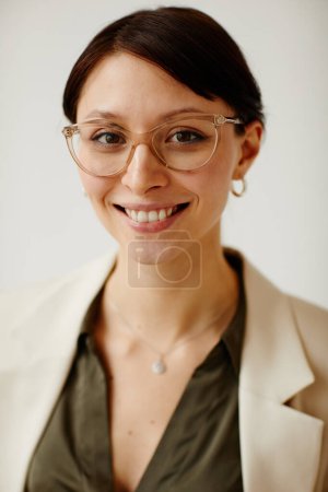 Vertikales Porträt einer jungen Unternehmerin, die eine Brille trägt und in die Kamera lächelt