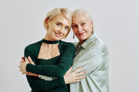 Photo for Minimal waist up portrait of smiling senior woman with adult daughter both looking at camera in studio - Royalty Free Image