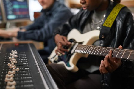 Photo for Close up of young black woman playing guitar and singing while composing music in professional recording studio, copy space - Royalty Free Image