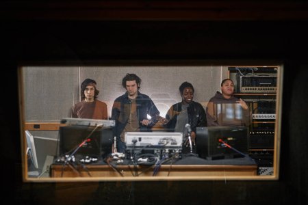 Téléchargez les photos : Portrait graphique de divers groupes de musique composant un nouvel album dans un studio d'enregistrement professionnel derrière un mur de verre - en image libre de droit
