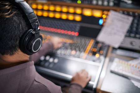 High angle view at music producer wearing headphones at audio workstation in professional recording studio, copy space