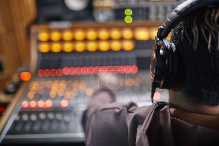 Photo for Back view at young musician wearing headphones at audio workstation in professional recording studio, copy space - Royalty Free Image