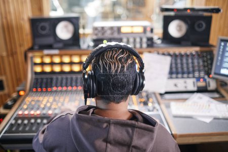 Photo for Back view at anonymous young musician wearing headphones in professional recording studio, copy space - Royalty Free Image