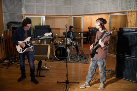 Foto de Retrato de larga duración de la banda de música alternativa tocando instrumentos en un estudio de grabación profesional - Imagen libre de derechos