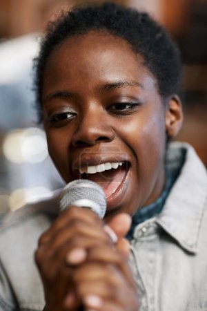 Photo for Close up portrait of talented black woman singing to microphone with passion for music and art - Royalty Free Image