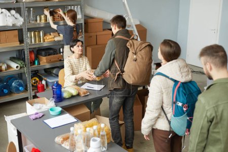 Foto de Vista de alto ángulo de los voluntarios que dan comida a las personas en línea en el centro de donación de refugiados - Imagen libre de derechos