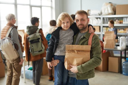 Photo for Waist up portrait of father and son holding food donations at volunteer center for refugees and people in need, copy space - Royalty Free Image