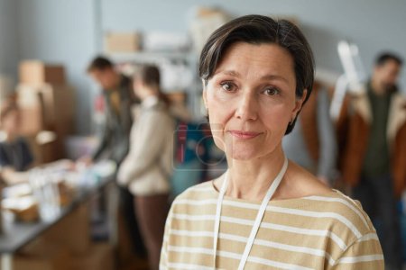 Portrait of mature Caucasian woman looking at camera while volunteering at help center for refugees, copy space