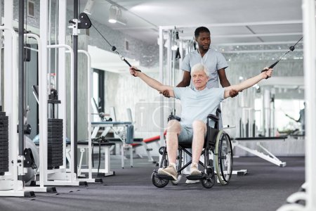 Foto de Retrato completo del hombre mayor en silla de ruedas haciendo ejercicios físicos en el gimnasio en la clínica de salud, espacio para copiar - Imagen libre de derechos