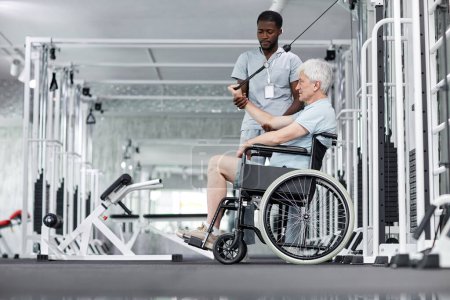 Photo for Side view portrait of senior man in wheelchair doing exercises in gym at healthcare clinic, copy space - Royalty Free Image
