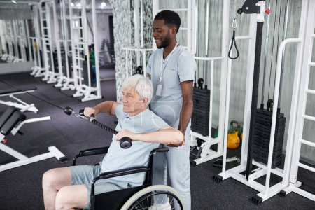 Photo for Portrait of African American rehabilitation therapist assisting senior man using wheelchair in gym, copy space - Royalty Free Image