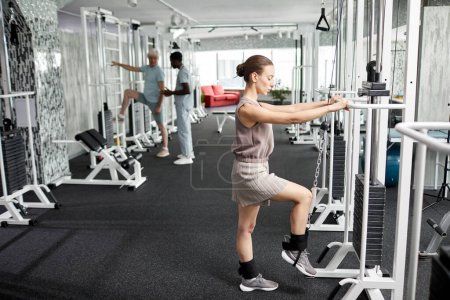 Photo for Side view portrait of smiling young woman doing rehabilitation exercises at gym in clinic, copy space - Royalty Free Image