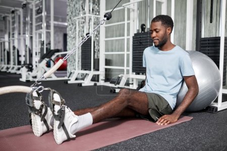 Téléchargez les photos : Portrait de jeune homme afro-américain faisant des exercices de réadaptation en salle de gym à la clinique de physiothérapie, espace de copie - en image libre de droit