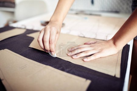 Foto de Manos de costurera usando tiza para delinear el patrón de costura de cartón en la tela cuando se trabaja en el taller - Imagen libre de derechos