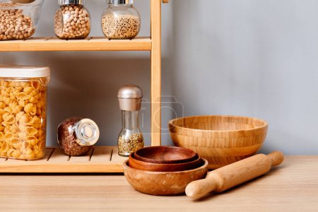 Photo for Arrangement of groceries in kitchen with wooden empty bowls on table - Royalty Free Image