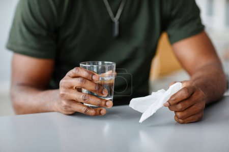 Photo for Unrecognizable young Black military man sitting at desk holding paper napkin and glass of water sharing his problems to psychologist - Royalty Free Image