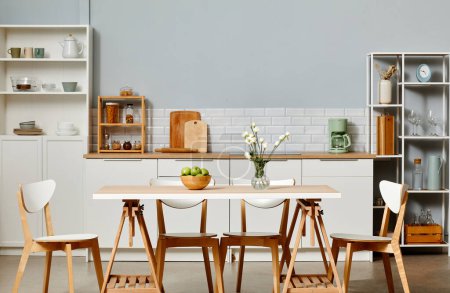 Photo for Minimal kitchen interior in white color with wooden accents and dinner table in foreground, copy space - Royalty Free Image