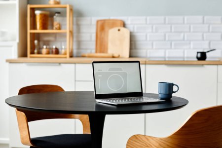 Téléchargez les photos : Minimal lieu de travail à domicile avec ordinateur portable ouvert sur table de cuisine noire avec chaises en bois, espace de copie - en image libre de droit