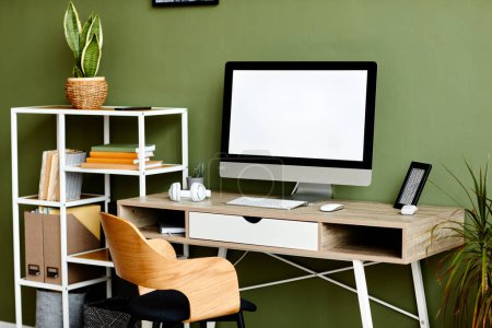 Foto de Imagen de fondo del lugar de trabajo con la computadora en blanco en la mesa de madera contra la pared verde, espacio de copia - Imagen libre de derechos