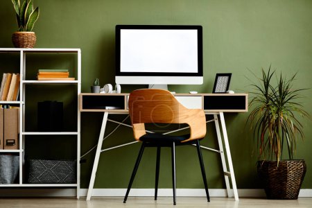 Foto de Imagen de fondo del lugar de trabajo gráfico de la oficina en casa con la computadora en la mesa de madera contra la pared verde, espacio de copia - Imagen libre de derechos