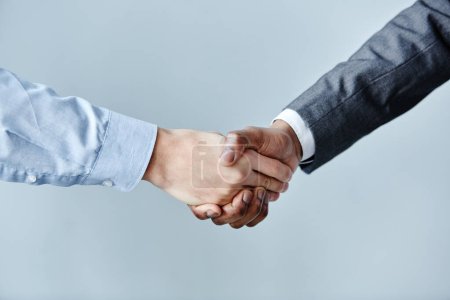 Téléchargez les photos : Gros plan minimal de deux hommes d'affaires serrant la main sur un simple fond bleu, espace de copie - en image libre de droit