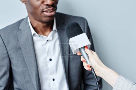 Téléchargez les photos : Coupé coup de succès homme d'affaires noir parlant au microphone tout en donnant interivew - en image libre de droit