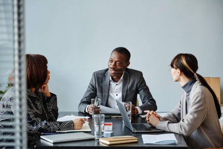 Téléchargez les photos : Portrait de jeune homme d'affaires noir parlant à l'équipe lors d'une réunion au bureau contre un mur bleu pâle, espace de copie - en image libre de droit