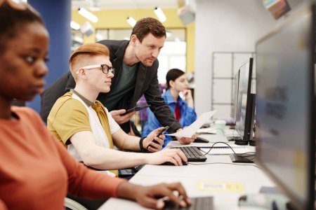 Foto de Vibrante retrato de un profesor masculino observando a los estudiantes usando computadoras en el aula de la universidad - Imagen libre de derechos