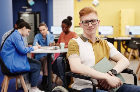 Téléchargez les photos : Portrait vibrant de jeune homme aux cheveux roux handicapé dans une bibliothèque collégiale regardant un appareil photo, espace de copie - en image libre de droit