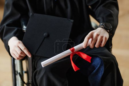 Foto de Primer plano del joven con discapacidad en la ceremonia de graduación en la universidad con diploma, espacio para copias - Imagen libre de derechos