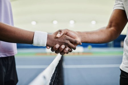 Photo for Close up of two tennis players shaking hands across net during match at court - Royalty Free Image