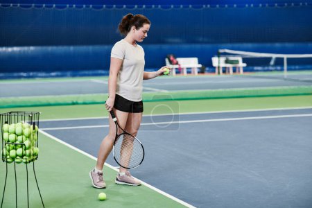 Foto de Retrato de larga duración de una joven caucásica jugando al tenis en una cancha cubierta, espacio para copiar - Imagen libre de derechos