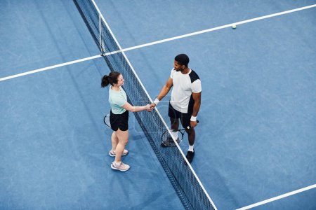 Photo for Minimal top view of two tennis players shaking hands across net during match, copy space - Royalty Free Image
