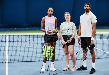 Téléchargez les photos : Portrait complet de jeunes debout au court de tennis et regardant tous la caméra, l'espace de copie - en image libre de droit