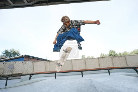 Foto de Retrato de adolescente haciendo trucos de skate en el aire en el parque de skate al aire libre en el área urbana - Imagen libre de derechos