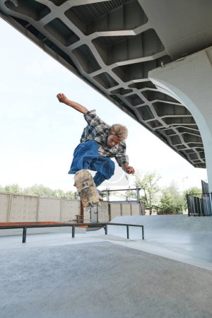 Téléchargez les photos : Portrait vertical d'un adolescent faisant des tours de skateboard dans l'air au skatepark extérieur en zone urbaine - en image libre de droit