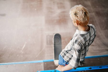 Téléchargez les photos : Vue de dessus minimale à l'adolescent garçon équitation planche à roulettes sur la rampe au parc de patinage et faire des tours, copier l'espace - en image libre de droit